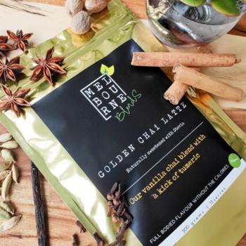 Turmeric Chai Latte packed in 200gr gold bag with black label position on timber board decorated with spices and flower