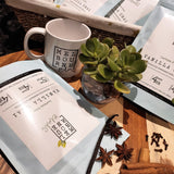 Lactose Free Vanilla Chai Latte packed in 200gr light blue bag with white label position on timber board decorated with spices, mug, and flower